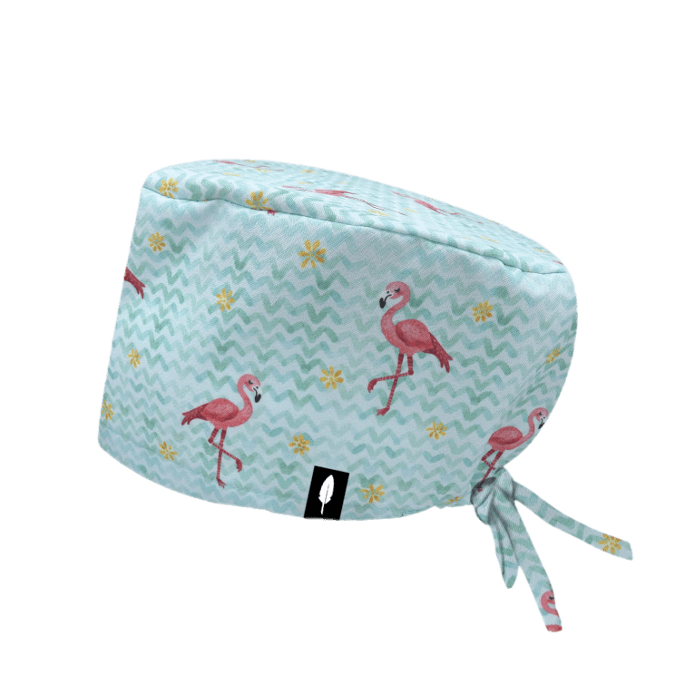 Gorro quirúrgico FLAMINGOS con estampado de flamencos rosados sobre fondo verde agua y detalles tropicales. Ideal para un look alegre y cómodo.
