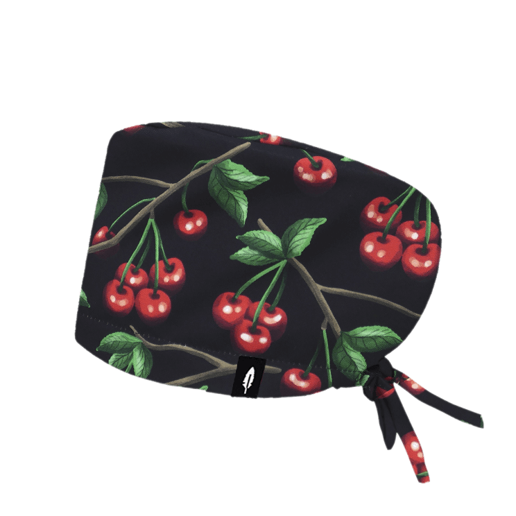 Gorro quirúrgico de poliéster en color negro con un vibrante diseño de cerezas rojas y hojas verdes, ideal para profesionales de la salud que buscan un estilo fresco y natural.