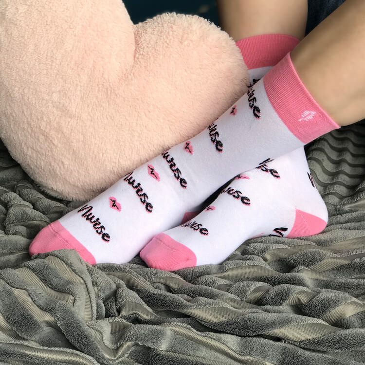 Calcetín de media caña NURSE con diseño de corazones y la palabra "Nurse" en colores blanco y rosa, fabricado en algodón peinado de alta calidad.