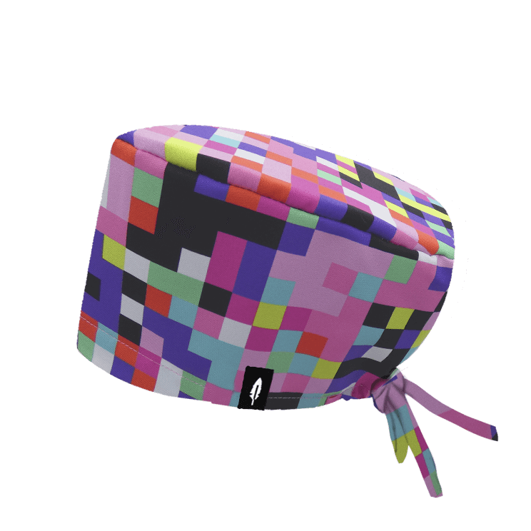 Gorro quirúrgico de pelo largo con diseño de píxeles en tonos rosas y multicolor, inspirado en videojuegos retro. Diseño de Robin Hat.