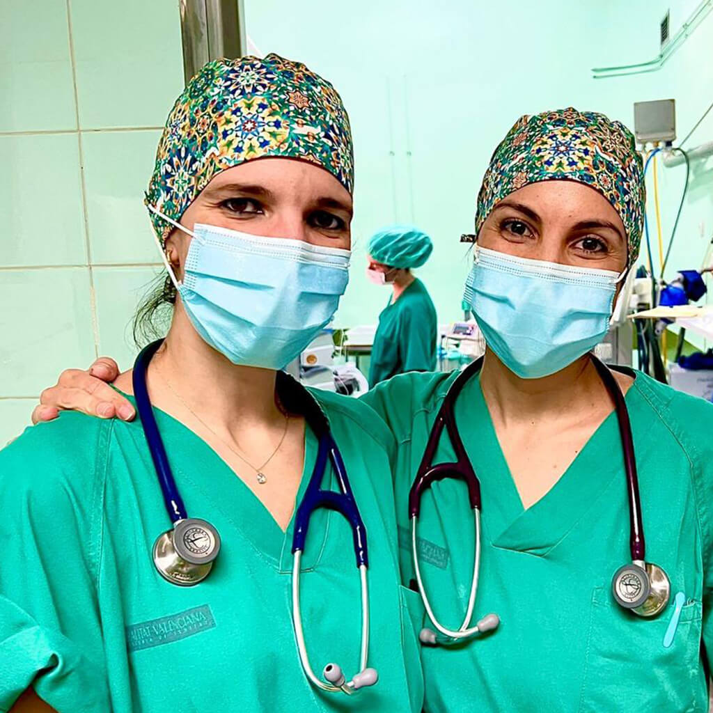 Dos profesionales sanitarias en quirófano usando gorro quirúrgico ALHAMBRA Robin Hat con diseño geométrico inspirado en azulejos de Granada, estetoscopios y mascarillas quirúrgicas