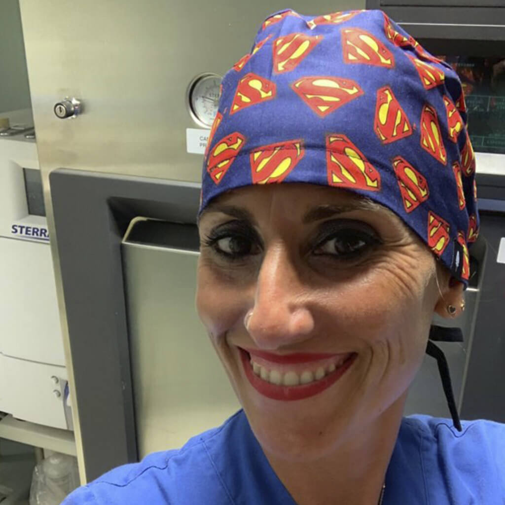 Profesional sanitaria sonriendo en hospital usando gorro quirúrgico SUPERMAN Robin Hat azul con logos rojos y amarillos, fabricado en algodón transpirable