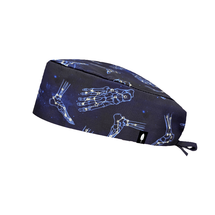 Gorro quirúrgico ASTROFOOT con constelaciones en forma de pies sobre azul marino. Tejido técnico ideal para quirófano y sala blanca.