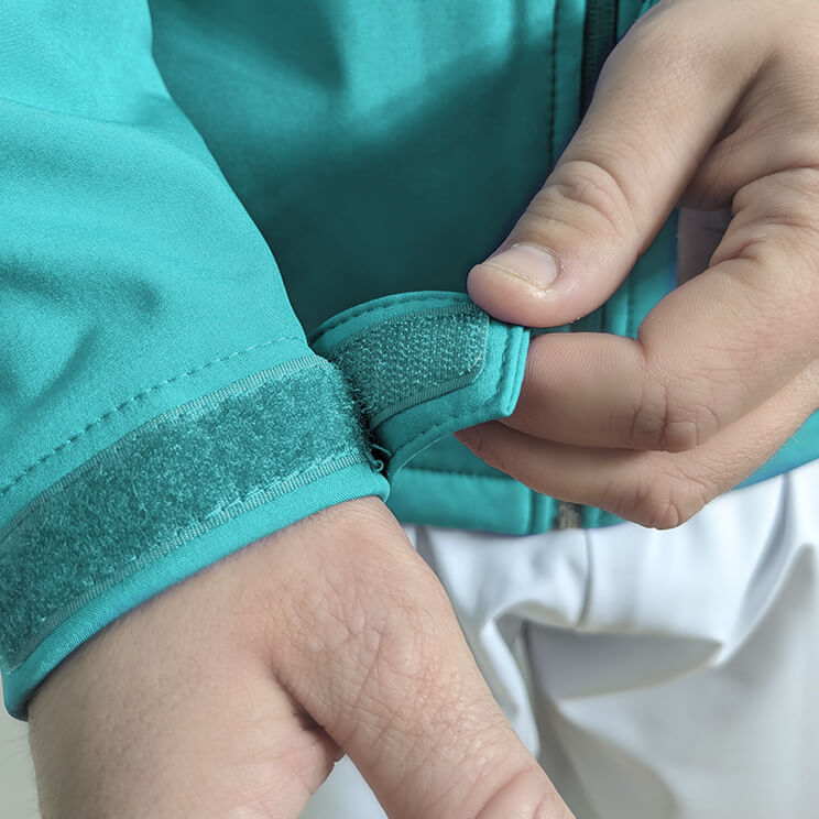 Chaqueta sanitaria turquesa softshell, equipada con cierre seguro, ajustes en las mangas y bolsillos funcionales, perfecta para uso en entornos clínicos.