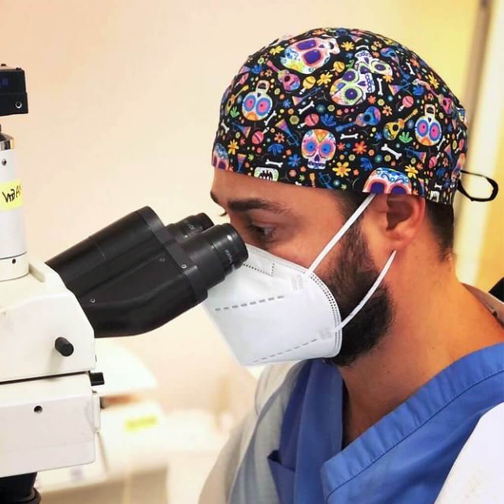 Dentista realizando tratamiento odontologico con gorro quirurgico Catrina de Robin Hat, diseño de calaveras y elementos del Dia de los Muertos en colores vibrantes, ideal para clinicas dentales