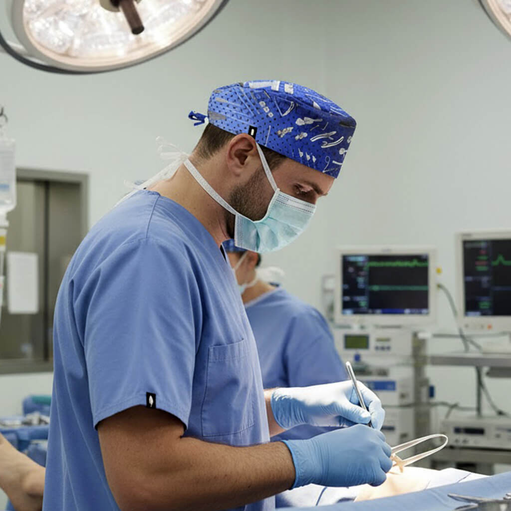 Cirujano en quirófano con gorro quirúrgico Trauma Kit azul con estampado de instrumental quirúrgico - Robin Hat