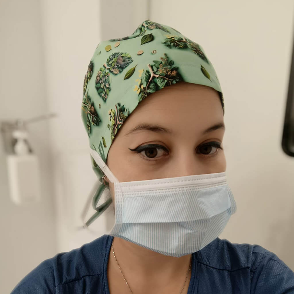 Profesional sanitaria usando gorro quirúrgico BREATHE de Robin Hat especializado en neumología con diseño de hojas verdes, llevando mascarilla en entorno hospitalario durante jornada laboral médica