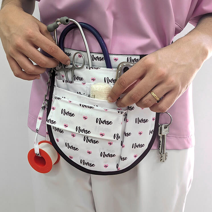 Riñonera sanitaria NURSE de poliéster blanco con diseño de texto "Nurse" y pequeños íconos de enfermería, ideal para profesionales de la salud.