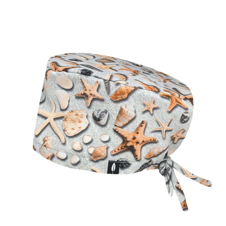 Gorro quirúrgico SEA TREASURES con estampado de estrellas de mar y piedras sobre fondo arena. Aporta frescura y estilo a tu uniforme