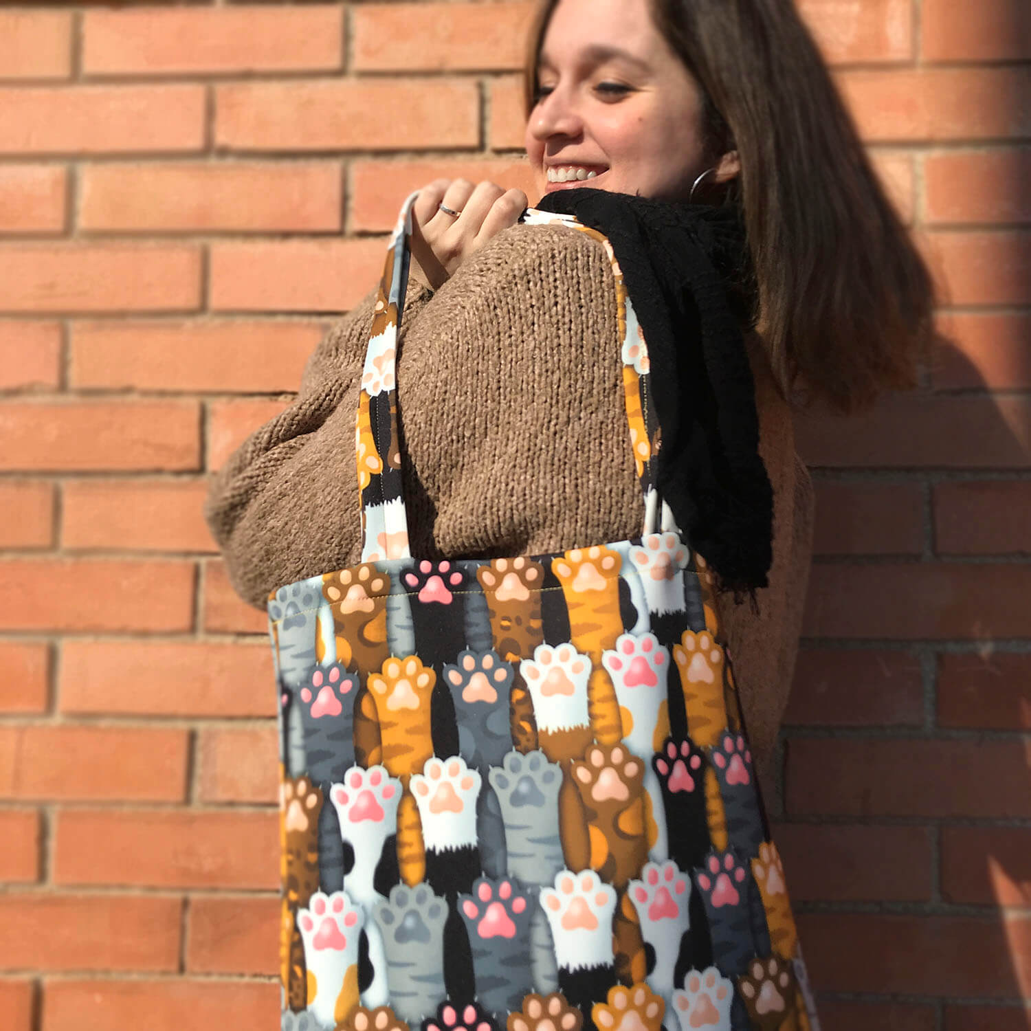 Tote Bag de Robin Hat con diseño de huellas de gato en fondo negro, con colores principales como marrón, gris, blanco y negro. Resistente al agua y anti-manchas.