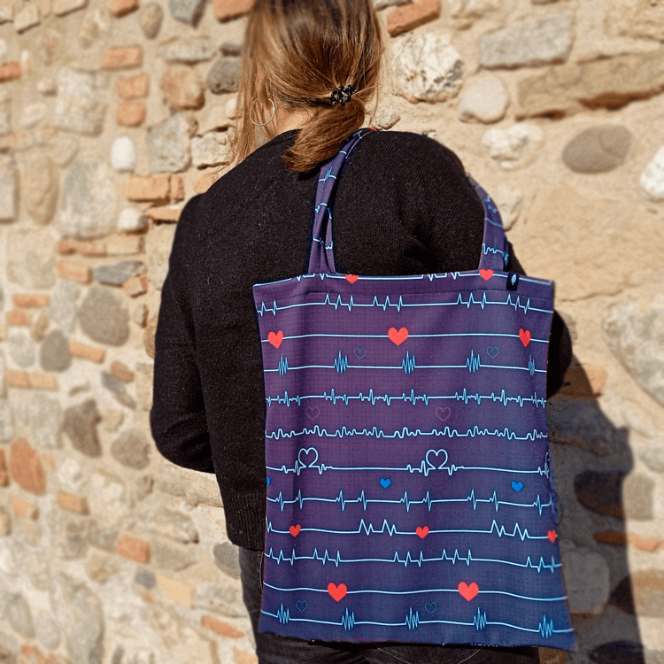 Tote Bag de Robin Hat con diseño de electrocardiograma en fondo azul, con corazones rojos.