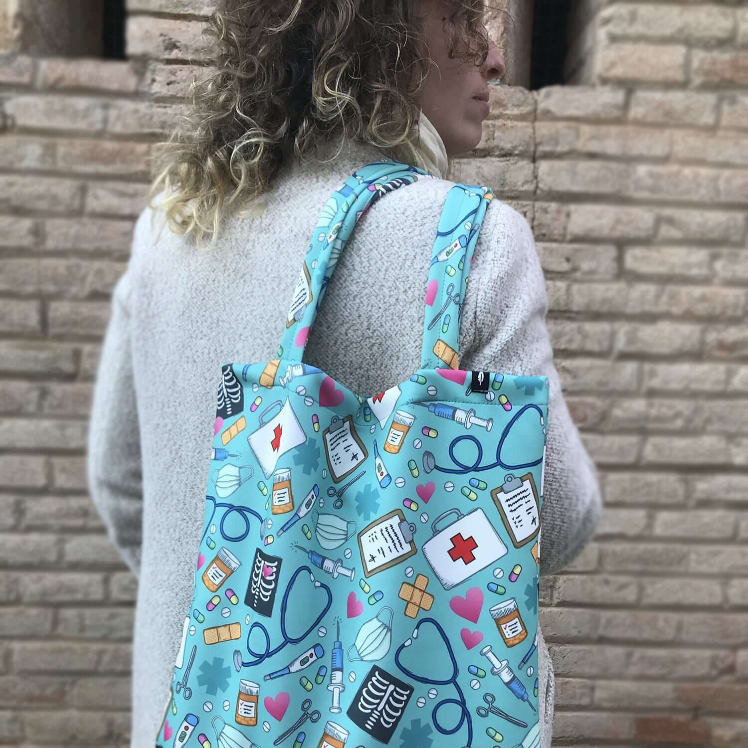 Tote Bag de Robin Hat con diseño de elementos médicos en fondo azul claro, ideal para profesionales de la salud.